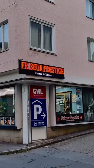 Eingang von Friseur Prestige in Bregenz mit rot leuchtendem Schild
